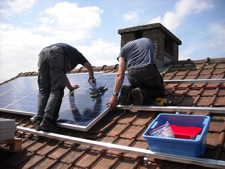 Men Installing Solar Panels On The Roof Top